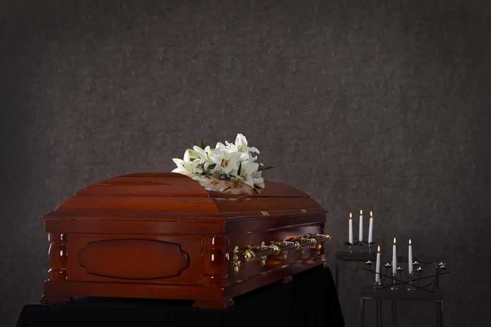 Wooden casket with white lilies and lit candles