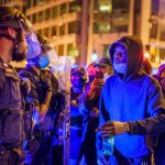 Protesters talk with police officers at night in city street
