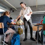 Teacher handing out papers in a classroom