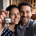 Smiling couple holding house keys while taking a selfie