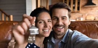 Smiling couple holding house keys while taking a selfie