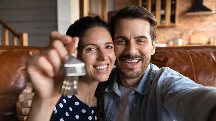 Smiling couple holding house keys while taking a selfie
